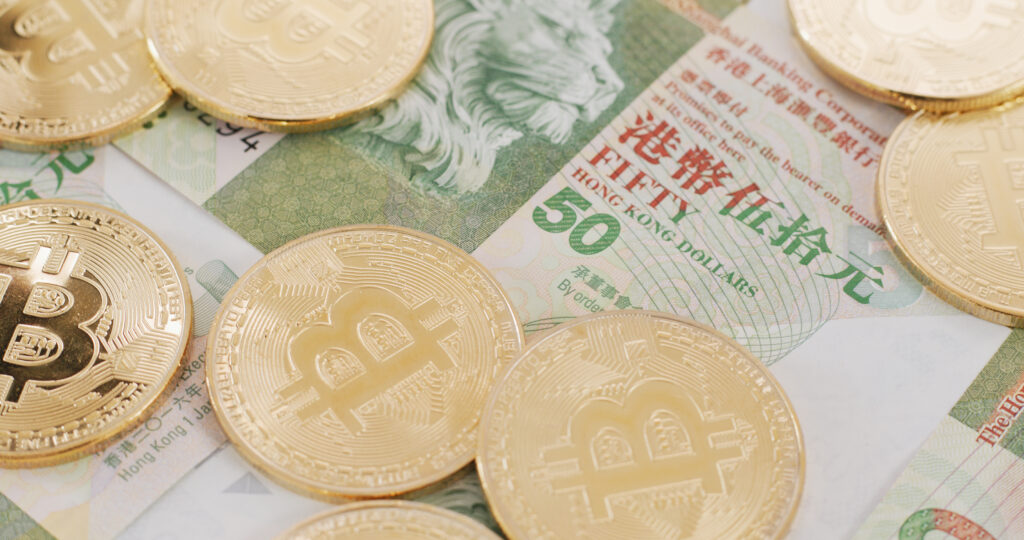 A few golden bitcoins on top of 50-dollar Hong Kong bills.