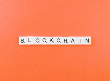 scrabble tiles spelling "blockchain" on an orange background.