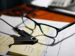 Glasses and nano wallet on a folder with documents, bills and notes on a desk
