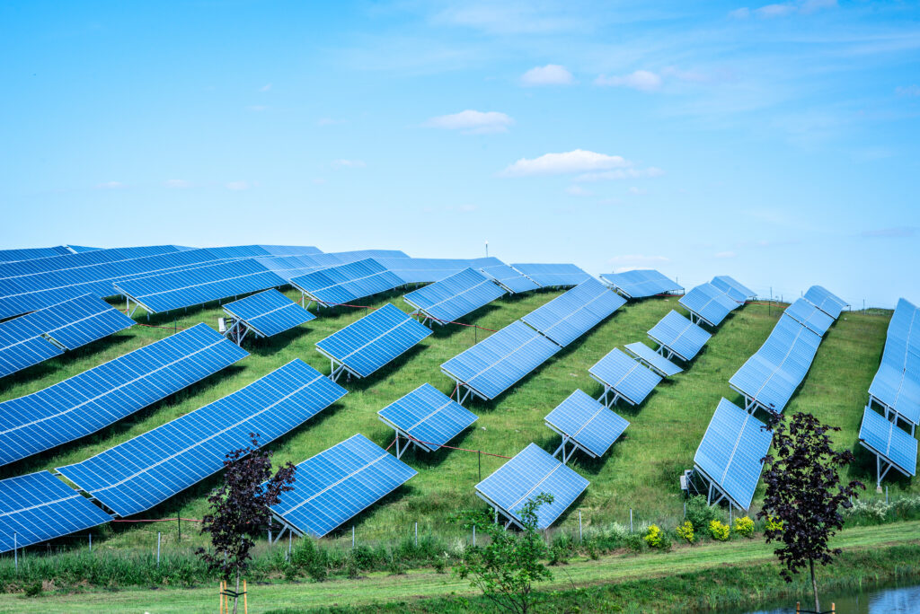 Solar panels against blue sunny sky produce green, environmentally friendly energy from sun. Blue solar panel background of photovoltaic modules for renewable energy.