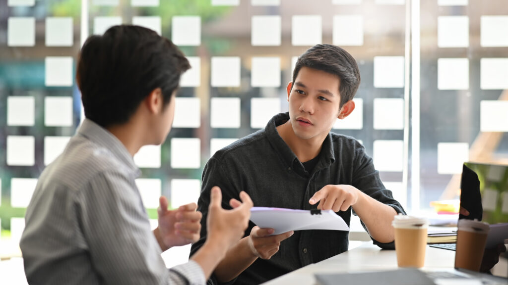 Asian young man consulting with paper document on modern office.