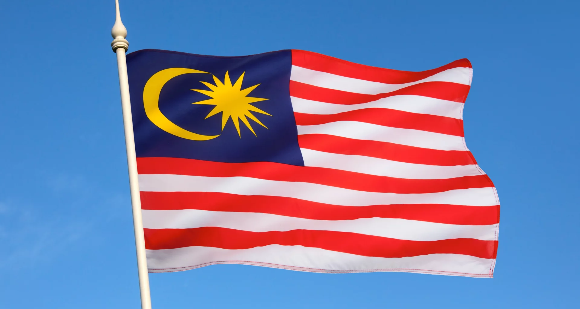 malaysian flag flying in front of a clear blue sky