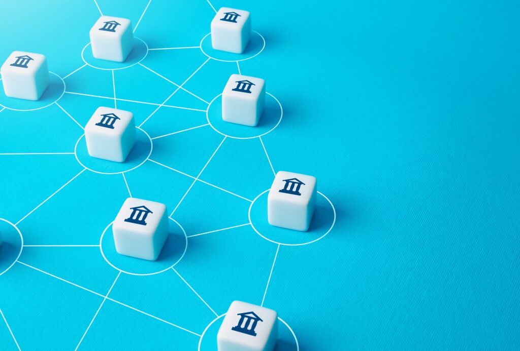 Little cubes sit on a blue surface interconnected by lines drawn between them, representing the blockchain and its applications.