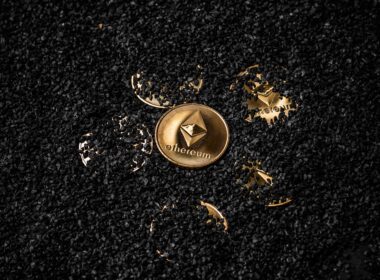 A gold ethereum coin in the middle of other buried ethereum coins