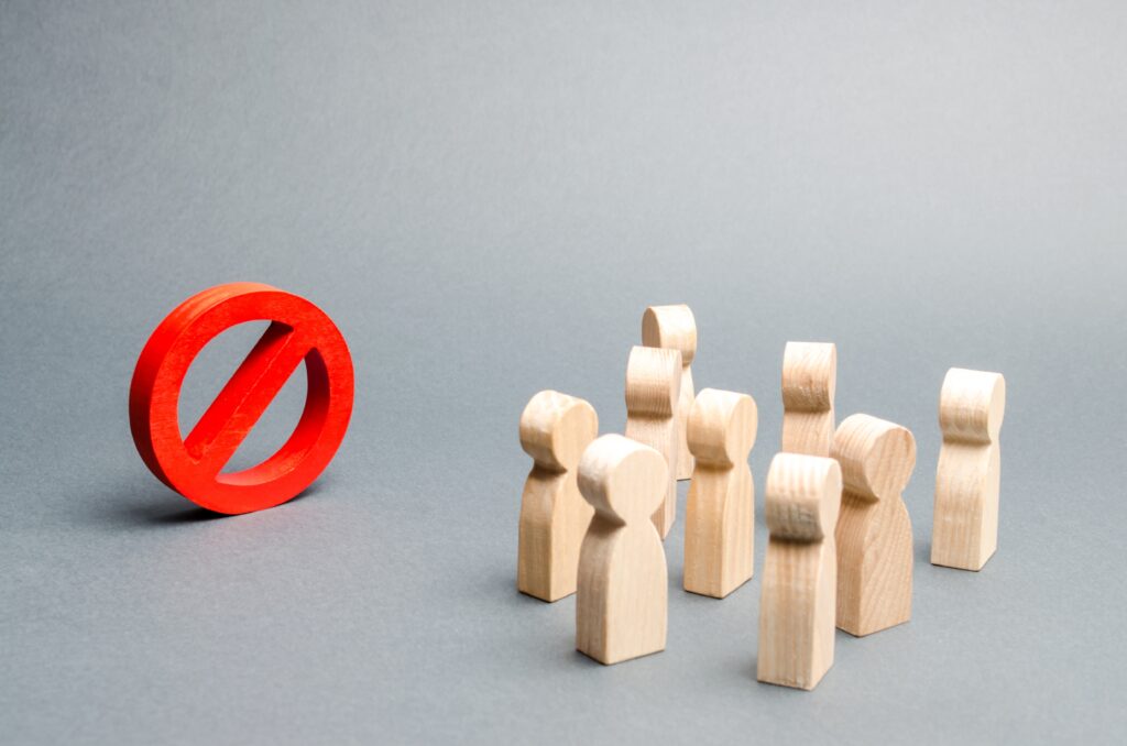 A crowd of wooden human-figure cutouts next to a red stop sign.