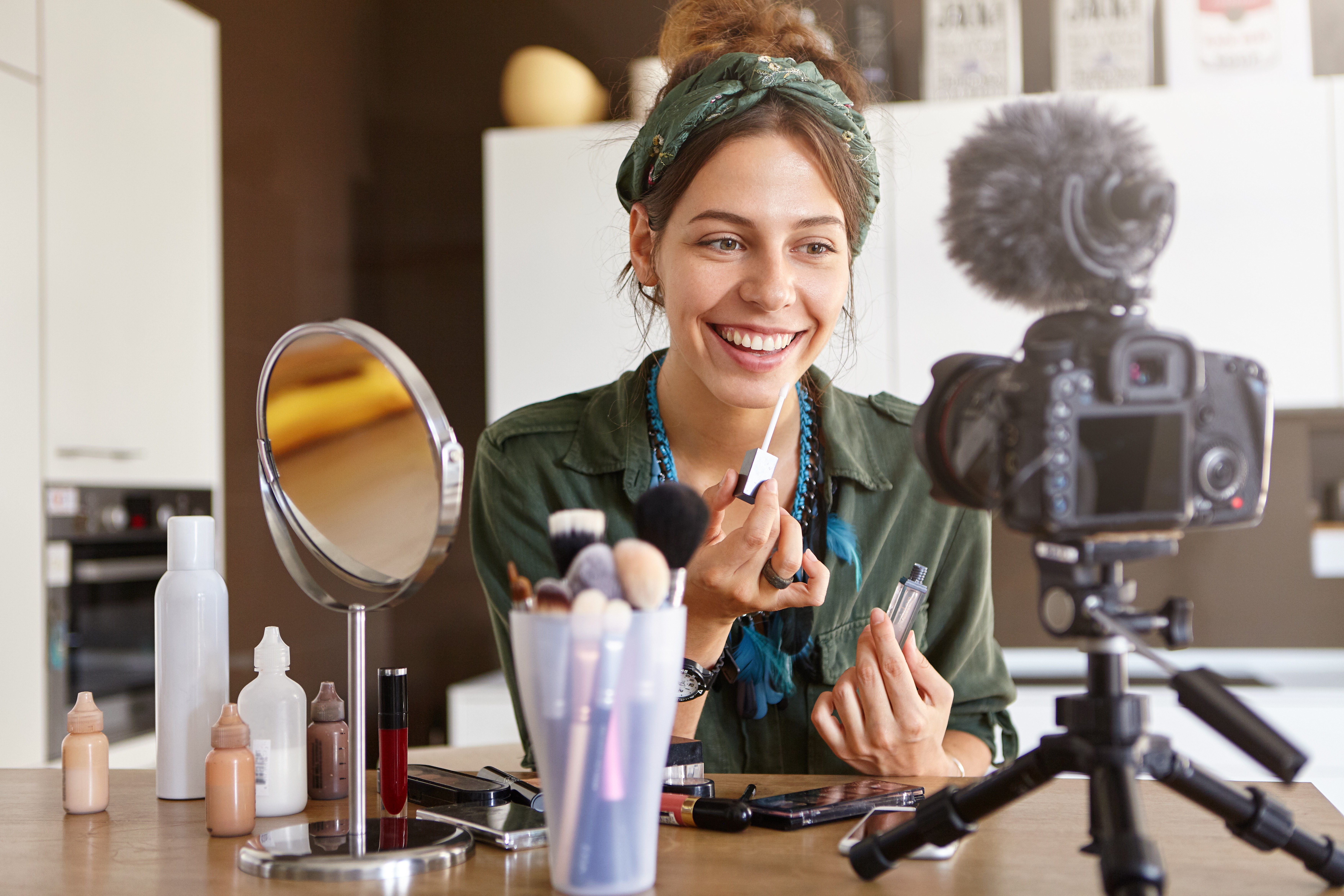 A woman is applying makeup in front of a camera. She is an influencer and doing this is her job.