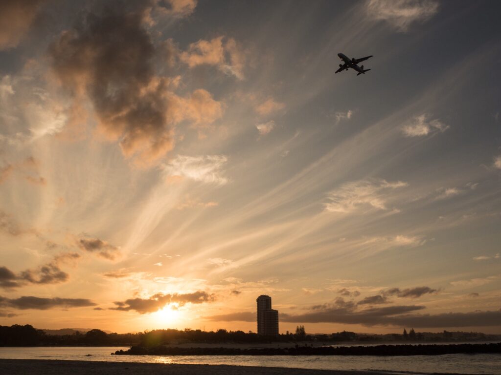 A plane flying over a city in the distance.