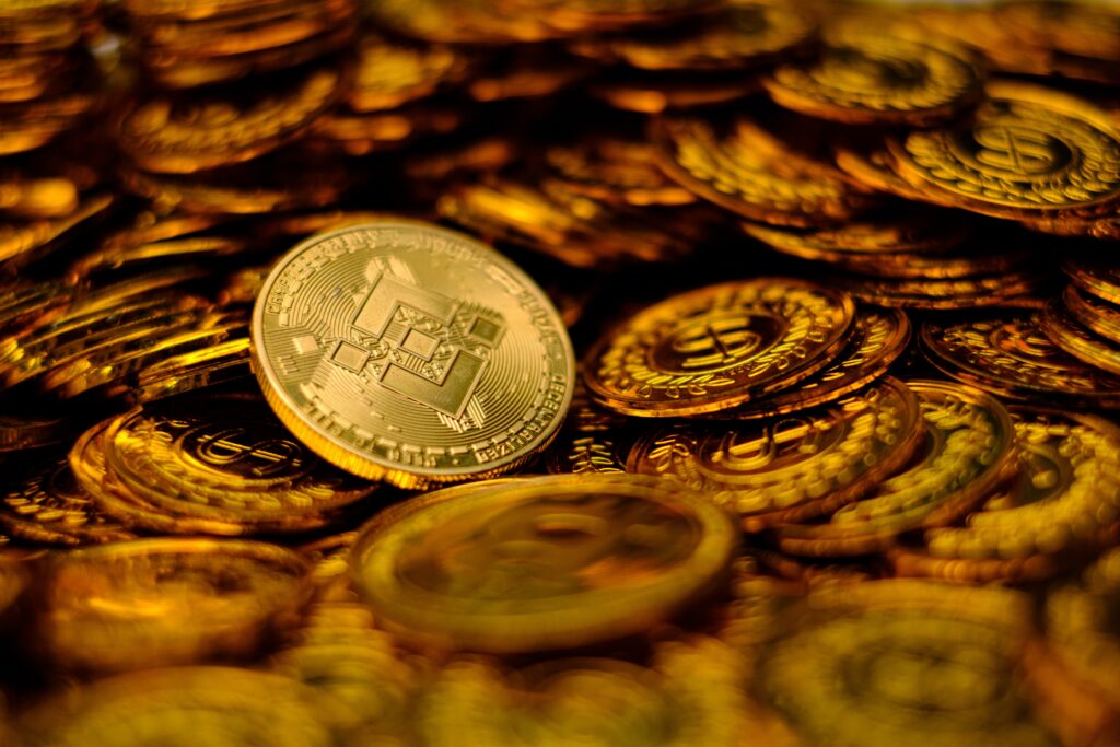 A gold Binance coin sits on top of a pile of other gold coins.