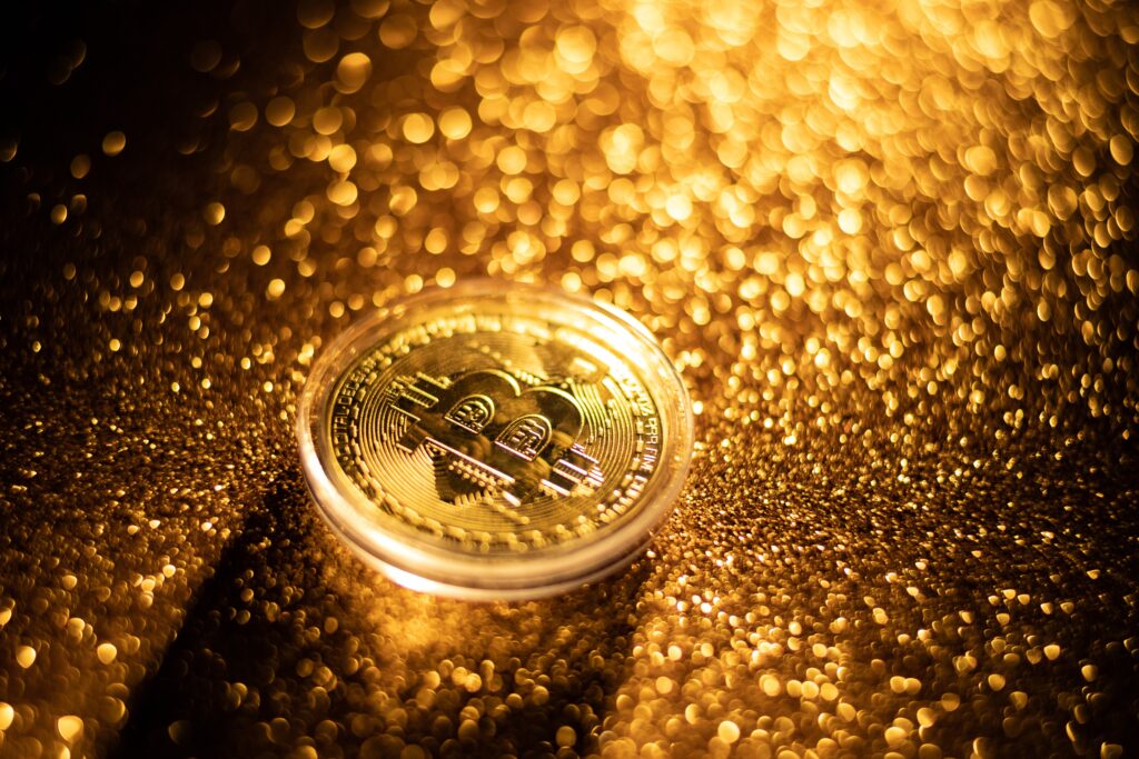 Bitcoin sitting on a shimmering gold surface

