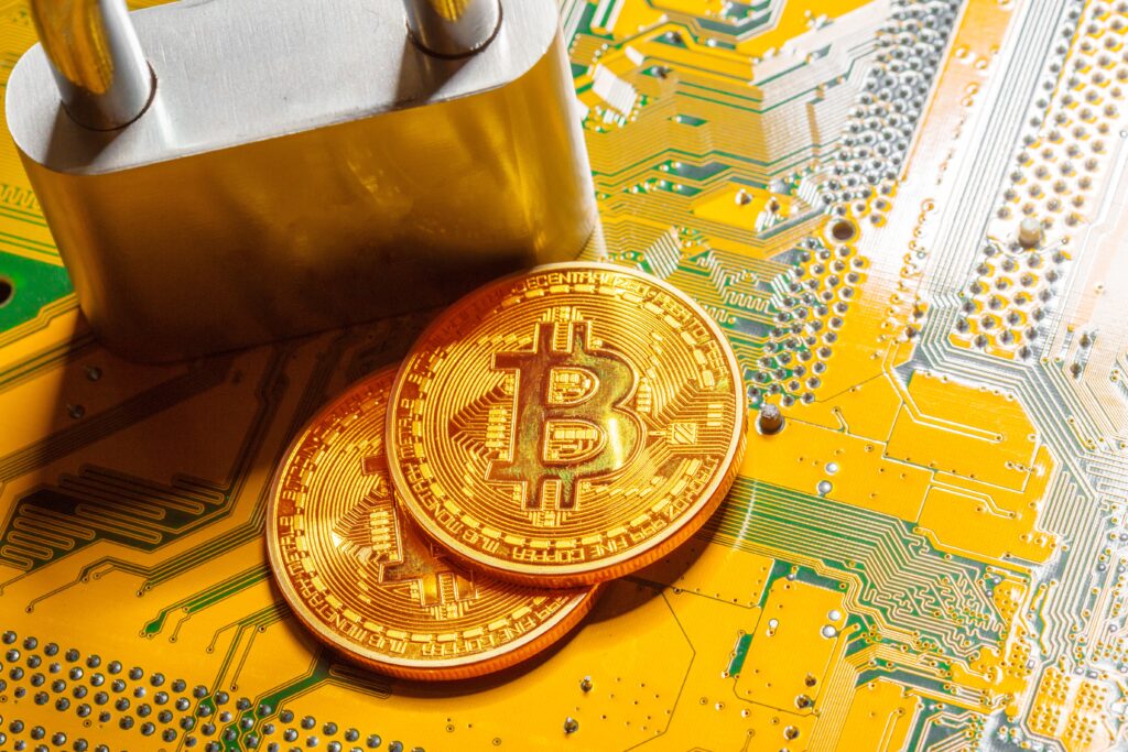 2 Bitcoins and a padlock sitting on a yellow circuit board