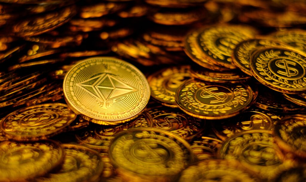 A gold Ether coin sits on top of a pile of nondescript gold coins.