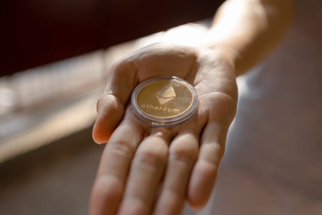 A gold Ether coin rests on an open palm.